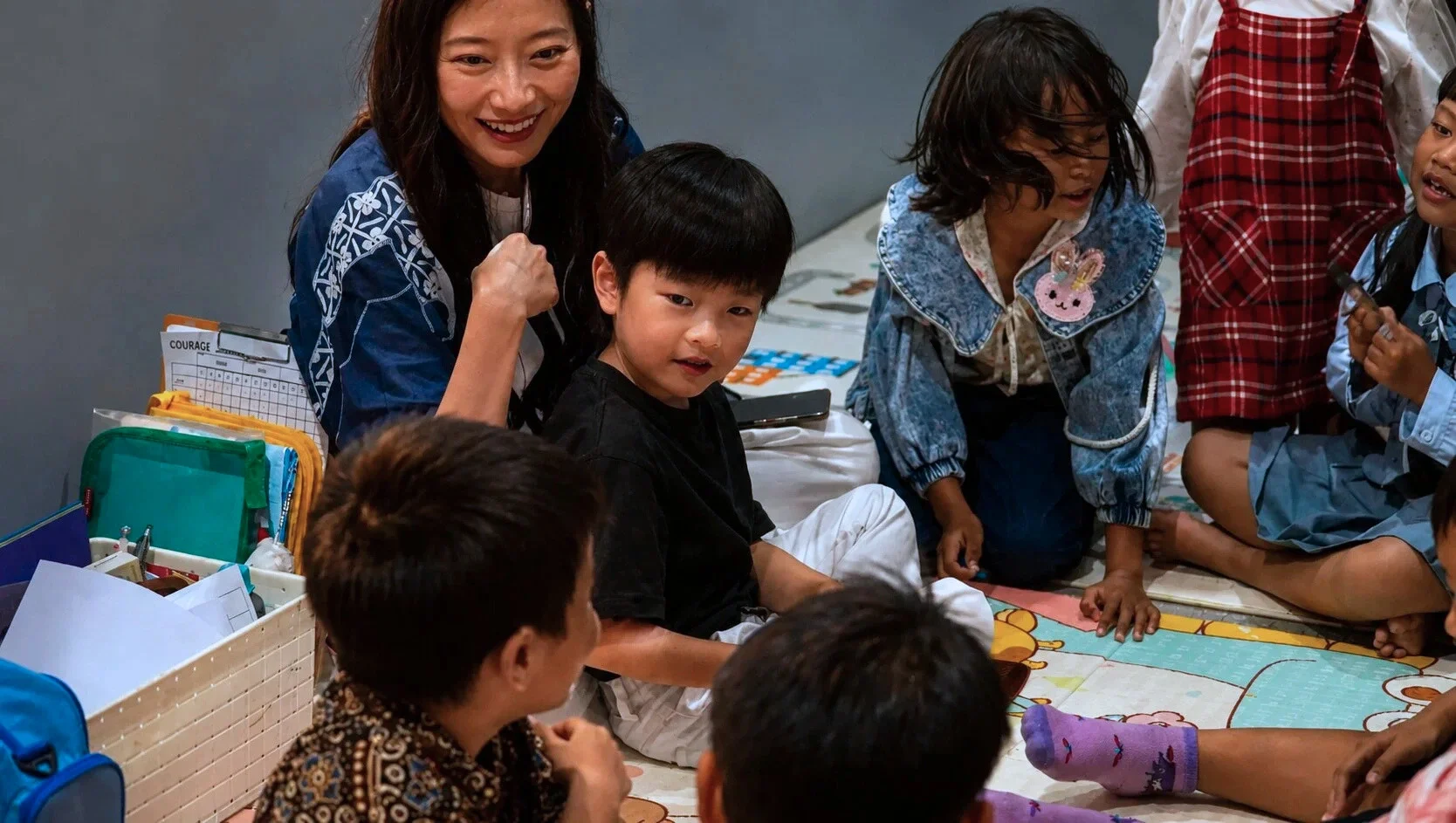 Anak kecil belajar di lantai bersama guru wanita