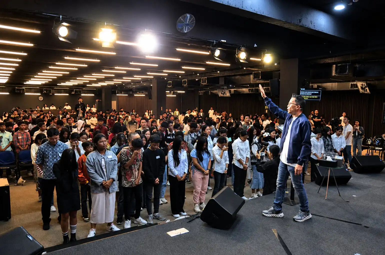 Pembicara di panggung dengan jemaat penuh saat altar call KKR Restart